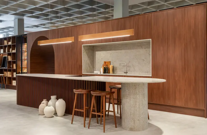 Espaço gourmet com bancada em madeira, banquetas e nicho iluminado